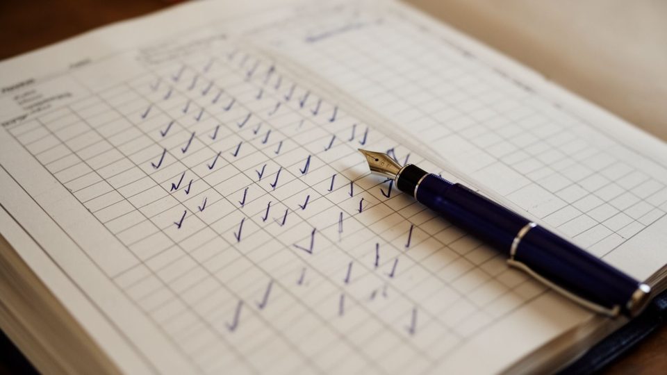Illustration: an attendance register page with blue tick marks and a fountain pen