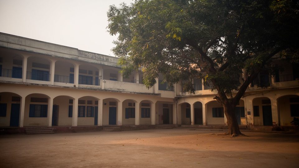 Illustration: an empty school courtyard in early morning with a neem tree and arched corridors